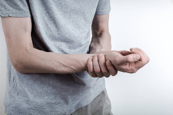 The man holds on to her sore wrist. The wrist joint disturbs the man. Inflamed hand. - Fotografie, Obrázek