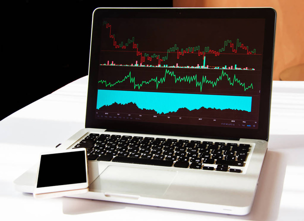 Анализ инвестиционных схем и графиков на ноутбуке. Смартфон с черным экраном. Авторское пространство. Бизнес-технологии
 - Фото, изображение