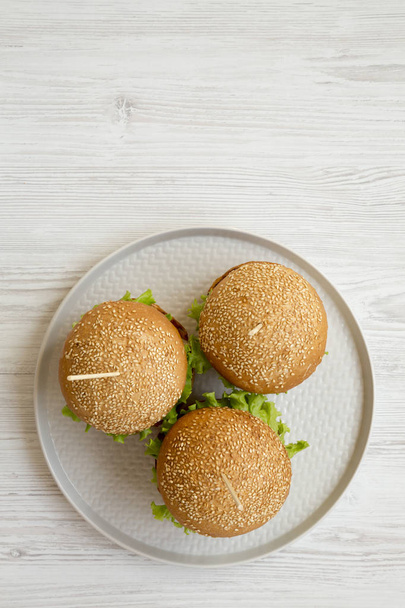 Cheeseburger auf grauem Teller über weißem Holzgrund, Draufsicht. Kopierraum. - Foto, Bild