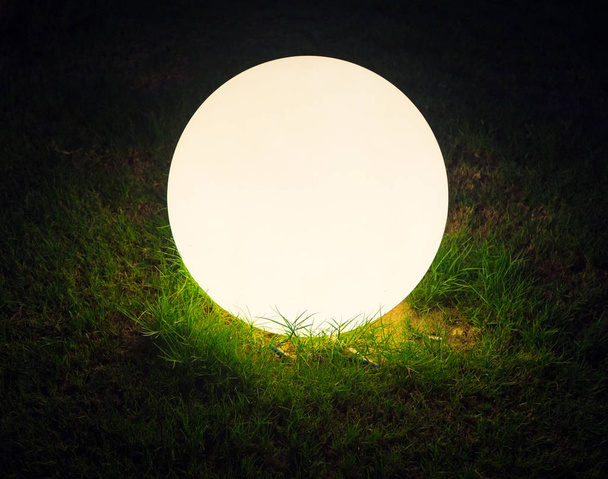Bright glowing ball in the grass with black background - Photo, image