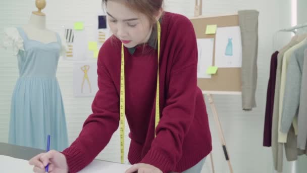 Giovane donna asiatica stilista disegno a matita e guardando la carta mentre si lavora nello studio di laboratorio
. - Filmati, video