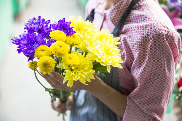 Donna che tiene in mano un mazzo di fiori gialli e viola
 - Foto, immagini