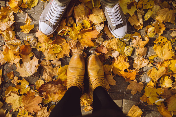 season and people concept - couple's feet  with autumn leaves on ground - Fotó, kép