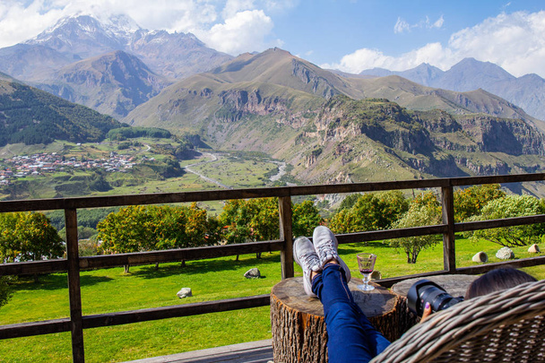 STEPANTSMINDA, GEORGIE - 15 septembre 2018 : Fille prend une photo selfie sur la terrasse Chambres Hôtel Kazbegi du sommet de la haute montagne Kazbek, montagnes du Caucase et Gergeti Trinity Church Tsminda Sameba
. - Photo, image