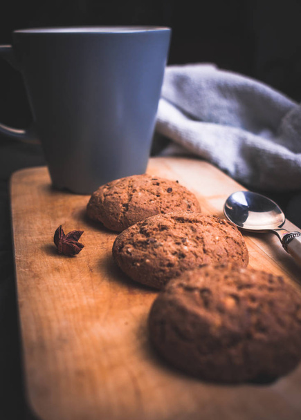 Чашка чаю з домашнім вівсяним печивом і ложкою на дерев'яній дошці
 - Фото, зображення