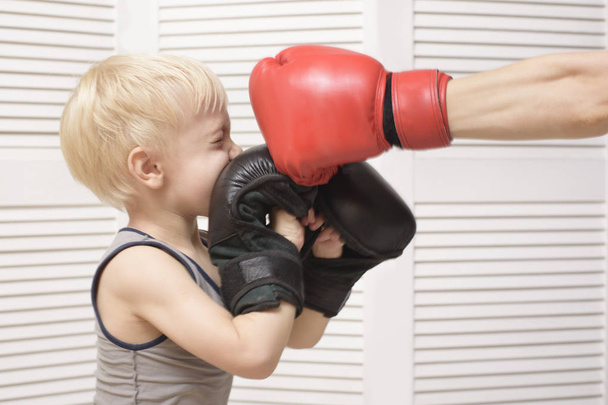 Blonder Junge boxt mit Hand in rotem Handschuh. Emotionen - Foto, Bild
