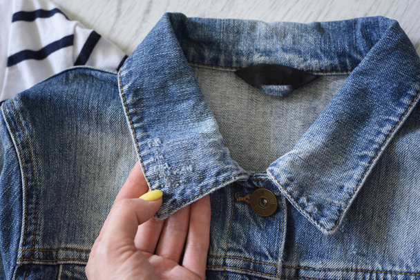 Collar of a denim jacket  in female hand. Fashionable concept - Photo, Image