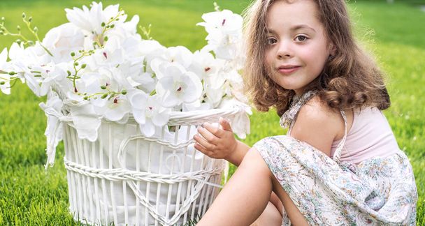 Retrato de un niño lindo sosteniendo una canasta de mimbre con plantas blancas
 - Foto, imagen