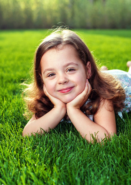 Portrait d'une adorable fille allongée sur une pelouse verte et fraîche
 - Photo, image