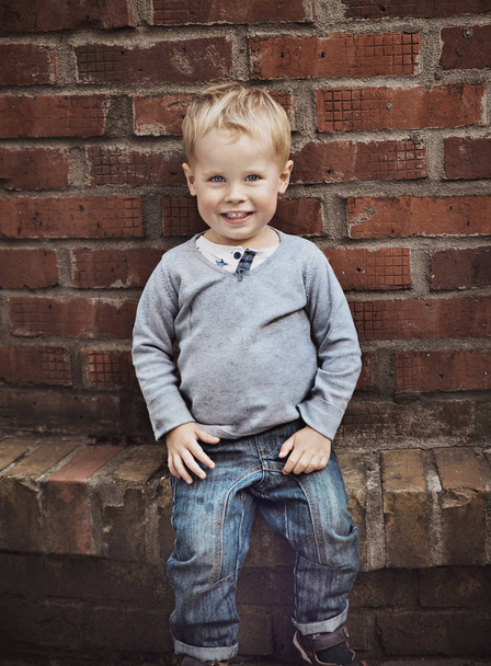 Cute little child posing over old, rusty wall - Фото, изображение