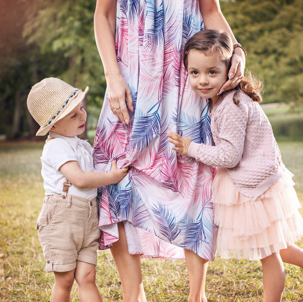Plachý, veselé děti drží všeobjímající matky noha - Fotografie, Obrázek