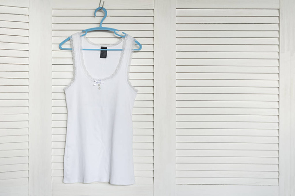 White jersey on the hanger. White shutters on the background - Photo, Image
