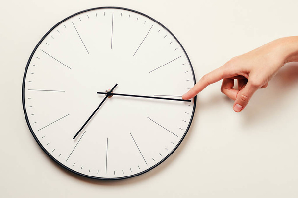 Χέρι γυναίκα σταματήσει το χρόνο σε ένα στρογγυλό ρολόι, χρόνος διαχείρισης και προθεσμία έννοια - Φωτογραφία, εικόνα
