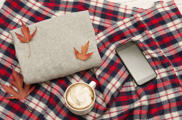 Szürke pulóver, kockás, kávé és szúró telefon. Őszi levelek. Divatos fogalom - Fotó, kép