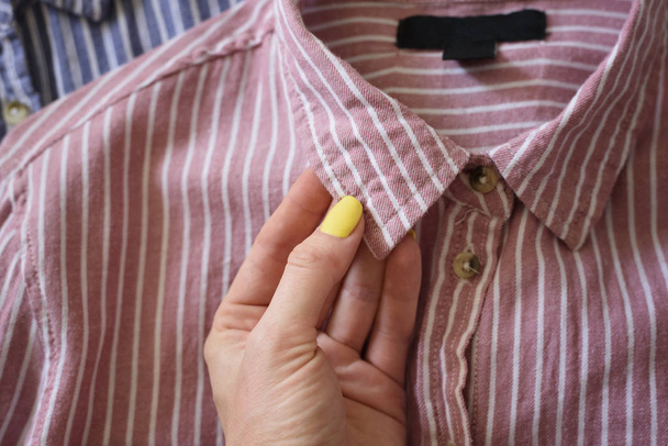 Kragen eines rosa Hemdes in weiblicher Hand. Modisches Konzept - Foto, Bild
