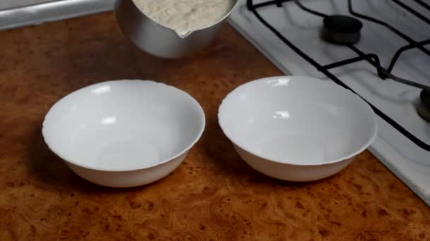 Cooking oatmeal, a woman razlazhivaet cooked porridge in plates, close-up, breakfast - Video