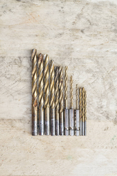 Set of drills of different size on a wooden background. Top view - Photo, Image