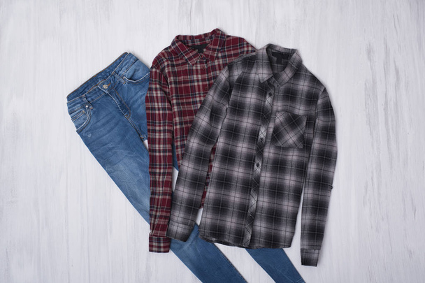 Checkered shirts and jeans on wooden background. Fashionable concept - Foto, imagen