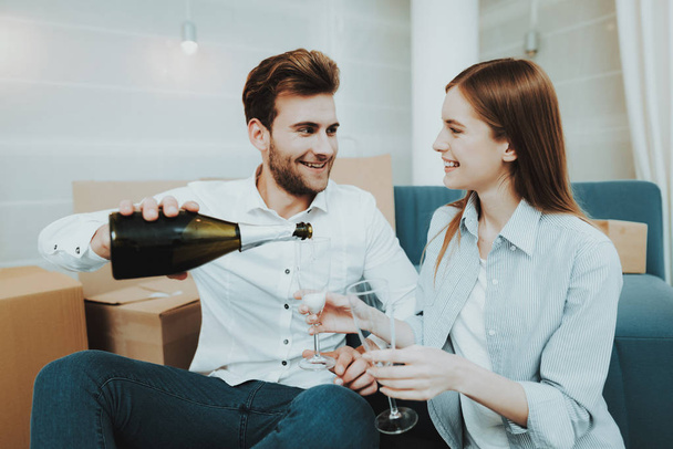 Young Couple In New Apartment. Champagne Celebrating. Love Each Other. Cheerful Sweethearts. New Life. Personal Flat. Happy Family. Domestic Life. Orange Boxes. Siting On The Floor. - Foto, afbeelding