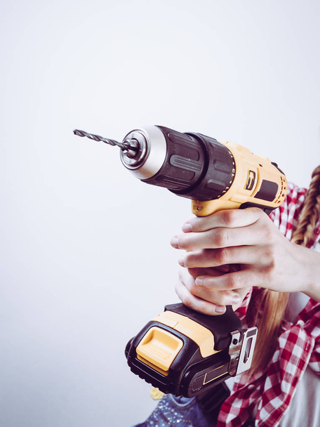 Unrecognizable woman holding yellow driller about to drill something. Hardware construction site objects concept. - Foto, imagen