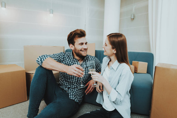 Young Couple In New Apartment. Champagne Celebrating. Love Each Other. Cheerful Sweethearts. New Life. Personal Flat. Happy Family. Domestic Life. Orange Boxes. Siting On The Floor. - Foto, Bild