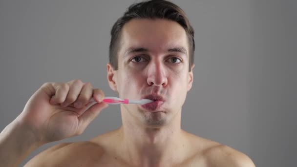 Young man brushing his teeth in bathroom and stop becuse of a tooth pain - Felvétel, videó