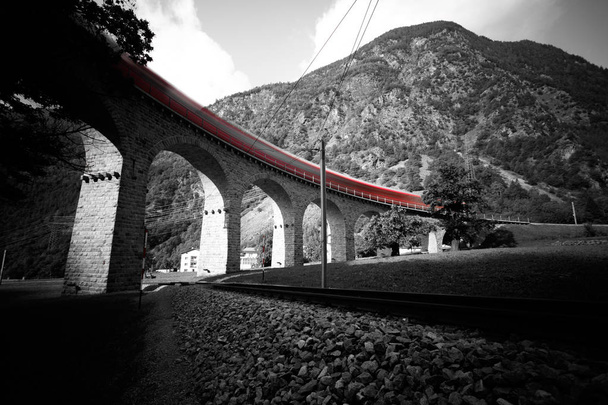 Train passing over the Brusio Spiral Viaduct in UNESCO landscape along the Bernina Railway Line. Val Poschiavo, Graubuenden, Switzerland. - Photo, Image