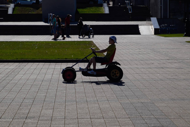 Children ride in the park on cars with pedals. Admiral Serebryakov Square. Childrens leisure. - 写真・画像
