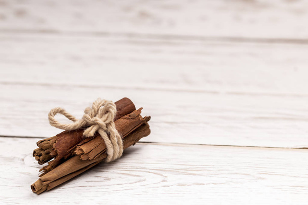 Cinnamon sticks tied with jute rope on whtie wooden background - Photo, image