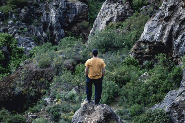 Back view of unrecognizable man standing on mountain edge and admiring picturesque view in nature in Cerro del Hierro, Seviile - Photo, Image