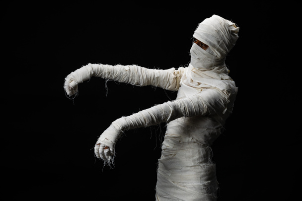 Студійний знімок портрета молодого чоловіка в костюмі, одягнений як хеллоуїн косплей страшної мумії позу, як зомбі, що діє на ізольованому чорному тлі
. - Фото, зображення