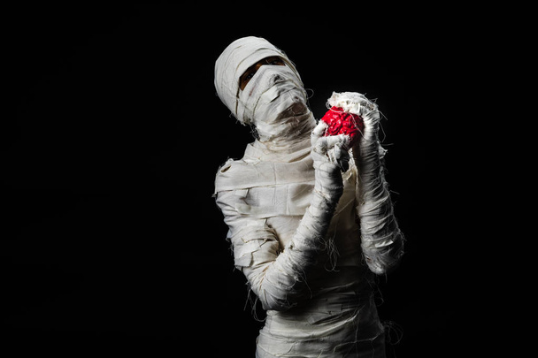 Studio shot portrait  of young man in costume  dressed as a halloween  cosplay of scary mummy holding fake brain acting on isolated black background. - Photo, Image