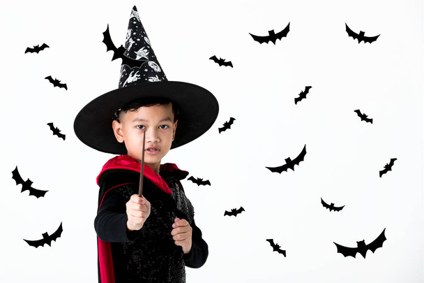 Young kid in witch costume dress holding magic wand  and point toward ahead with black shadow bat cutting in background. Concept for halloween funny activity and decoration. - Photo, Image