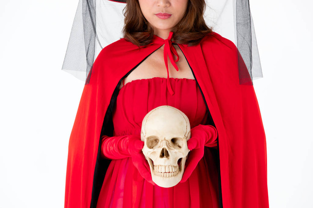 Beyaz zemin üzerine kırmızı elbise holding kafatası kadında. Kavramı kılık Cadılar Bayramı festivali için. - Fotoğraf, Görsel