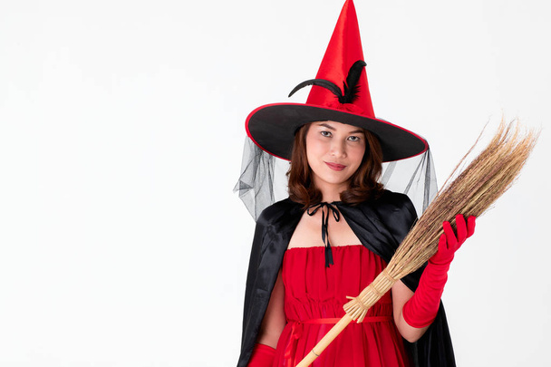 Mulher de vestido vermelho traje para famale bruxa segurando vassoura no fundo branco com espaço de cópia. Conceito para atividade engraçada no festival de Halloween
. - Foto, Imagem