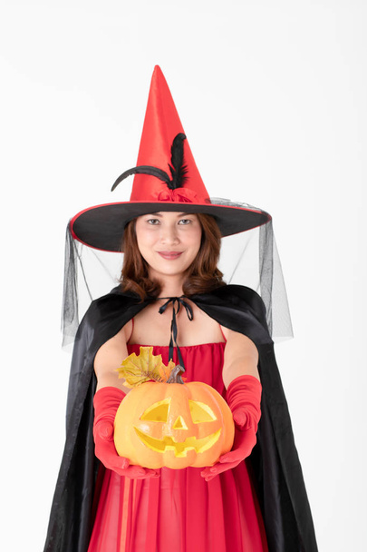 Studio shot Asian woman in red costume witch  hand holding a orange jack'O pumpkin isolated on white backgroung, concept for halloween fashion festival. - Photo, Image