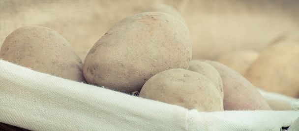Closeup of fresh potatoes in wicker basket, concept of healthy nutrition and vegetable harvest - Fotó, kép
