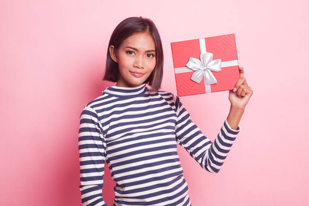 Young Asian woman with a gift box on pink background - Foto, Imagem