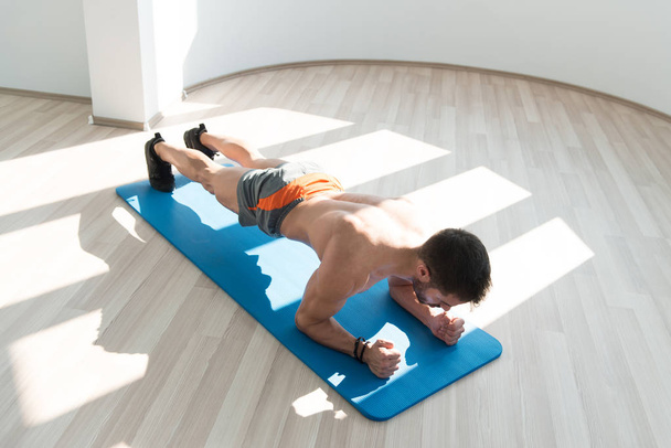 Young Man Athlete Doing Abs Exercise Elbow Plank As Part Of Bodybuilding Training - Foto, afbeelding