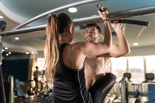 Young Couple Doing Pull Ups or Chin-ups Exercise in the Gym - Foto, afbeelding