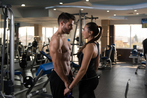 Portrait Of A Physically Fit Couple Showing Their Well Trained Body with Kettle Bell - Muscular Athletic Bodybuilder Fitness Model Posing After Exercises - 写真・画像