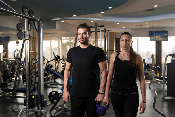Portrait Of A Physically Fit Couple Showing Their Well Trained Body with Kettle Bell - Muscular Athletic Bodybuilder Fitness Model Posing After Exercises - Photo, Image
