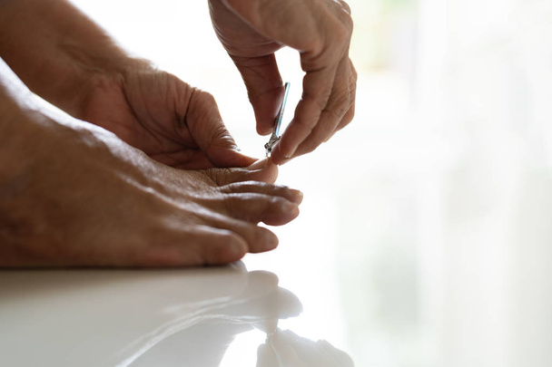 recorte de uñas, mujer mayor corte de pies uñas utilizando cortauñas sobre fondo blanco, primer plano - Foto, imagen