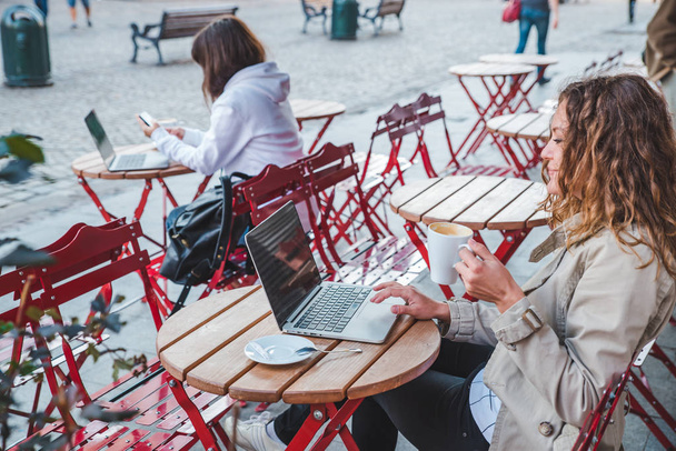 dwie kobiety w siedząc przy innym stole. latte pitnej. pracy na laptopie. koncepcja życia - Zdjęcie, obraz