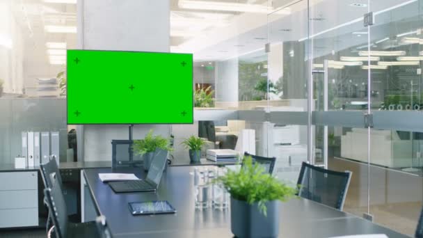 Современный пустой конференц-зал с большим конференц-столом с разнообразными дозами и топами на нем, на стене большой телевизор с зеленым цветным экраном
. - Кадры, видео