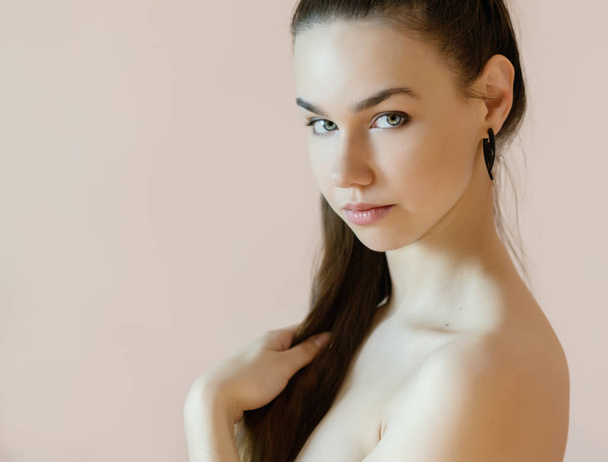 Portrait of a beautiful young woman on a beige background. Selective soft focus on eyes. - Foto, afbeelding