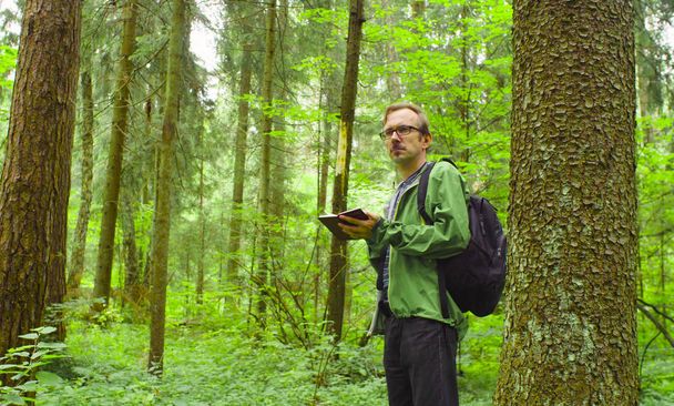 Οι οικολόγοι σε ένα δάσος γράφοντας στο Σημειωματάριο. - Φωτογραφία, εικόνα