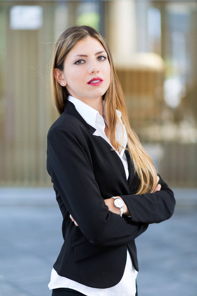 Confident young female manager with crossed arms outdoor in a modern urban setting - Foto, Bild
