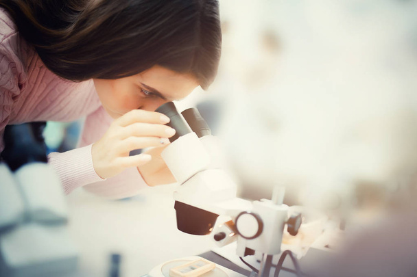 Menina olhando através de um microscópio
 - Foto, Imagem