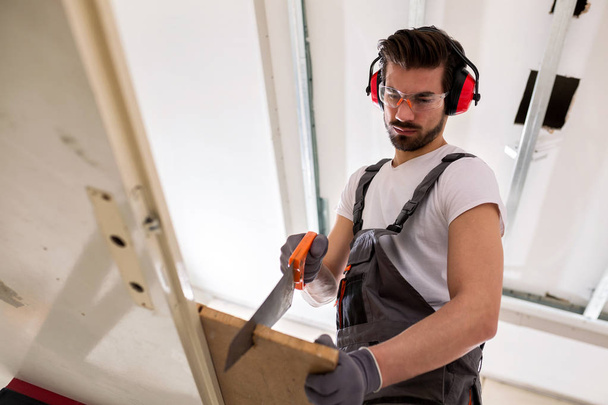 Attractive man doing some woodwork using only a rip saw - Foto, afbeelding